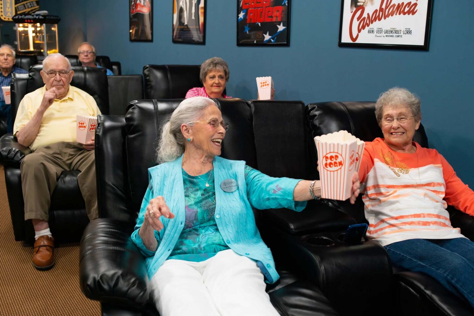 Seniors enjoying popcorn in a cozy movie theater setting.