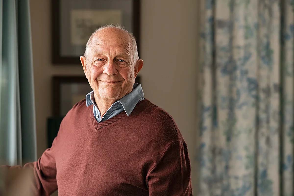 Smiling elderly man in a cozy indoor setting.