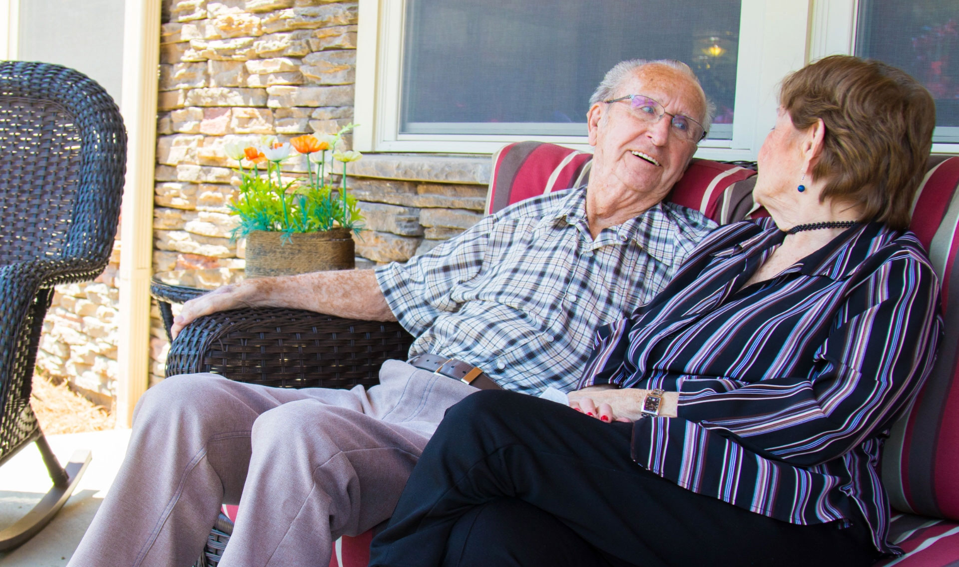 Elderly couple enjoying conversation on a porch.